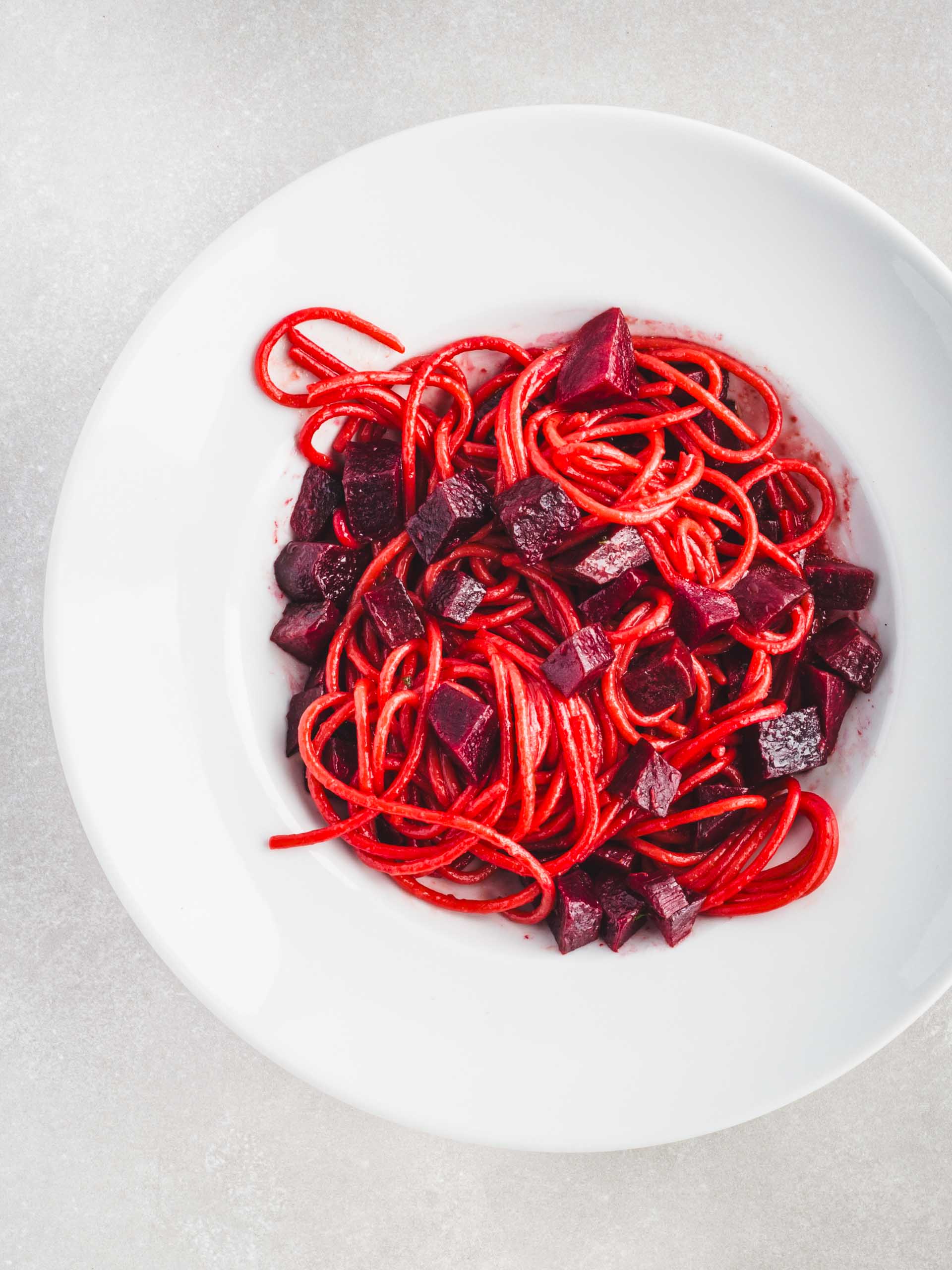 Beet pasta in a white pasta bowl.